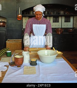 Victorien cuisine femme de ménage faisant de la pâtisserie dans l'ancienne cuisine à l'aide d'un rouleau à pâtisserie. Banque D'Images