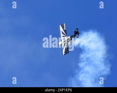 Champion américain 8KCAB Decathlon cascades d'avion volant avec de la fumée. Banque D'Images