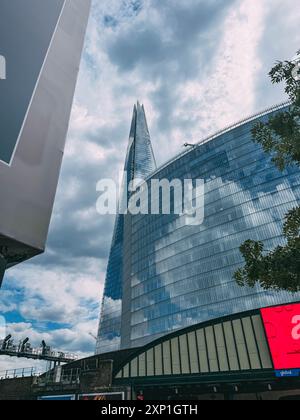 Un grand bâtiment avec un panneau rouge sur le côté. Le ciel est nuageux et le soleil n'est pas visible Banque D'Images