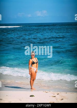 Une femme se tient sur une promenade en bois surplombant l'océan à nusa Lembonghan Banque D'Images