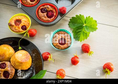 Muffins au lait caillé sucré garnis de fraises, dans une assiette sur une table en bois. Banque D'Images