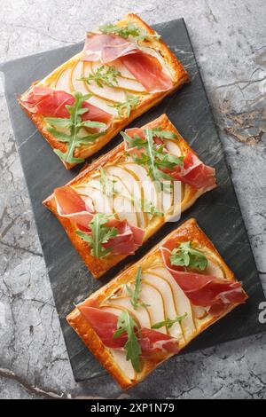 Tartes feuilletées à la poire jambon pour buffet et soirées gros plan sur planche de marbre sur table. Vue de dessus verticale Banque D'Images