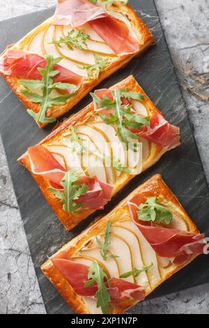 Sandwich feuilleté avec poire, jambon et roquette gros plan sur panneau de marbre sur la table. Vue de dessus verticale Banque D'Images