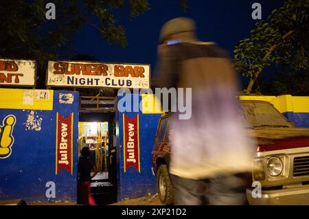 Figure floue entrant dans le Super Bar Night Club en Gambie, représentant la vie nocturne animée et le rassemblement social. Banque D'Images