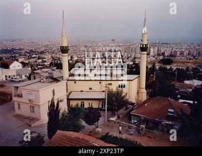 Une vue aérienne époustouflante d'une mosquée avec deux minarets, avec un panneau 'Allah' sur son toit, surplombant le paysage urbain d'Antalya, en Turquie. L'image capture la culture religieuse et le paysage urbain. Banque D'Images