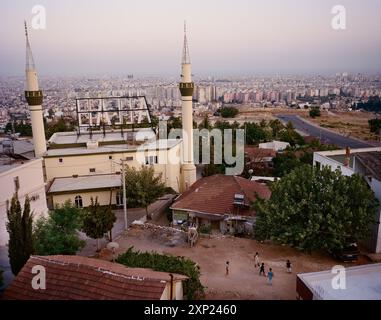 Superbe vue aérienne d'une mosquée avec deux minarets et le signe 'Allah' sur son toit surplombant le paysage urbain d'Antalya, Turquie au coucher du soleil. Banque D'Images