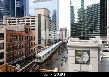 Vue surélevée d'un train de métro traversant le centre-ville de Chicago, États-Unis, au milieu de gratte-ciel classiques et modernes. La scène urbaine capture l'atmosphère animée et la diversité architecturale de la ville. Banque D'Images