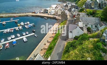 Gardenstown Aberdeenshire Écosse murs du port amarrés bateaux Seatown et Harbour Road et la mer bleu vert à marée haute en été Banque D'Images