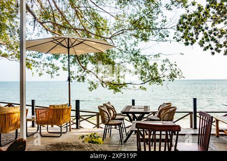 Tables, chaises et parasol dans un restaurant avec vue sur la plage de Tanjing Tokong à Penang, Malaisie Banque D'Images