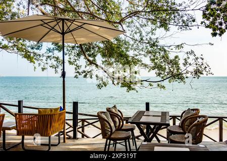 Tables, chaises et parasol dans un restaurant avec vue sur la plage de Tanjing Tokong à Penang, Malaisie Banque D'Images