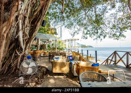 Tables et chaises dans un restaurant avec vue sur la plage de Tanjing Tokong à Penang, Malaisie Banque D'Images