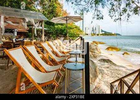 Tables et chaises longues dans un bar en bord de mer avec vue sur la plage de Tanjing Tokong à Penang, Malaisie Banque D'Images