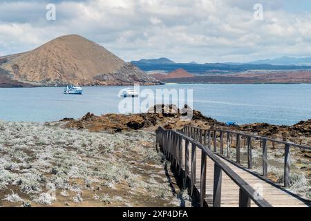 Promenade en bois à la baie tranquille avec des voiliers et des collines volcaniques en arrière-plan Banque D'Images