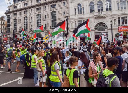 Londres, Royaume-Uni. 03 août 2024. Les manifestants tiennent des drapeaux palestiniens pendant la marche à Piccadilly Circus. Des milliers de personnes ont défilé en solidarité avec la Palestine pour exiger un cessez-le-feu et appeler le gouvernement britannique à cesser d’armer Israël alors que la guerre à Gaza se poursuit. Crédit : SOPA images Limited/Alamy Live News Banque D'Images