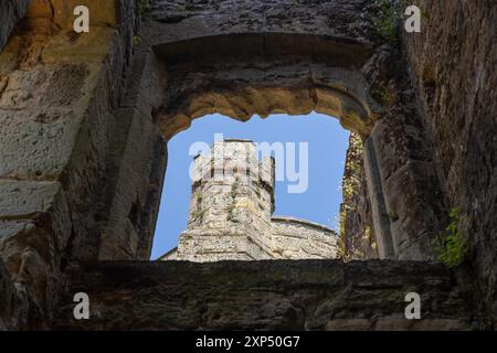 Vue à travers une fenêtre du château présentant une partie des remparts et des tours historiques du château de Bodiam, mettant en évidence son architecture médiévale et le design de la forteresse. Banque D'Images