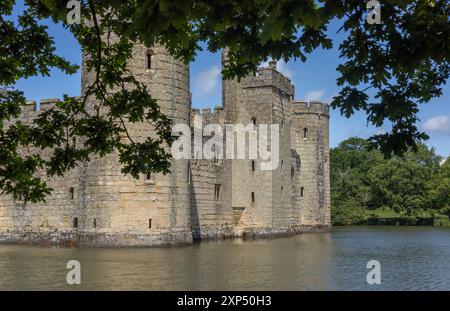 Murailles médiévales impressionnantes du château de Bodiam dans le Sussex de l'est, en Angleterre, reflétées dans ses douves environnantes sur un ciel bleu ensoleillé, jour d'été. Banque D'Images