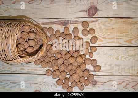 A versé des noix dans un panier en osier sur une table en bois. Vue de dessus. Banque D'Images