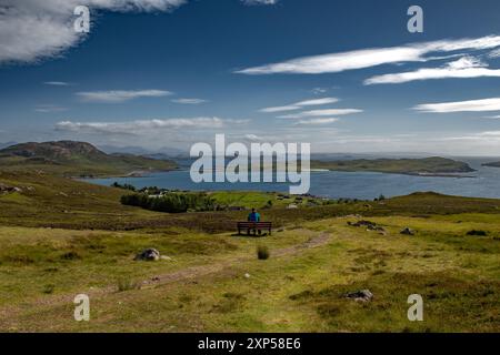 Femme célibataire sur le banc regarde la côte atlantique avec Summer Isles, Isle Ristol et Eilean Mullagrach près du village Altandhu dans les Highlands de Scotlan Banque D'Images