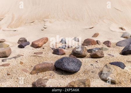 Rochers sur la plage de sable avec de grandes dunes de sable en toile de fond Banque D'Images