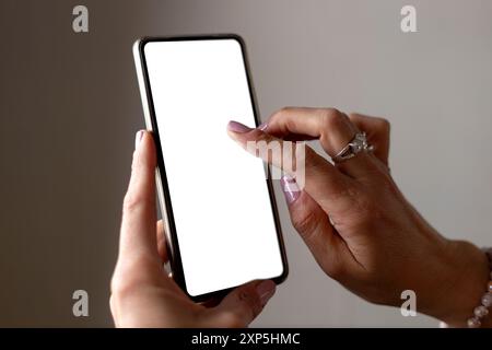 Main de femme tenant un téléphone portable avec écran vierge pour maquette. Banque D'Images