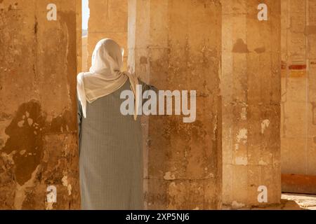 Un visiteur moderne regarde à travers les anciennes colonnes du temple d'Hatshepsout à Deir el-Bahari. Cette image saisissante capture la beauté intemporelle. Banque D'Images