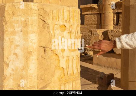 Suivez un doigt alors qu'il trace les anciens hiéroglyphes sur les murs du temple d'Hatshepsout. Cette image invite les spectateurs à se lancer dans un voyage à travers Banque D'Images