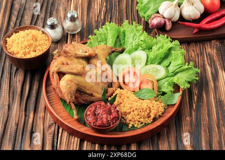 Ayam Goreng Kremes, style traditionnel indonésien de poulet frit avec pâte épicée à la farine de riz. Servi avec Sambal et Lalap Banque D'Images