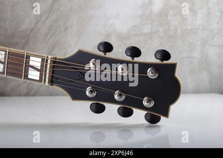 Instrument de musique - poupée peghead cou accordant PEG rétro fond de guitare acoustique d'un mur de béton avec un reflet ci-dessous Banque D'Images