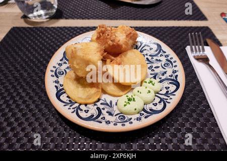 Morceaux de morue tempura avec chips de légumes et mayonnaise à l'aneth sur une plaque en céramique sur un napperon dans la table dans un restaurant Banque D'Images