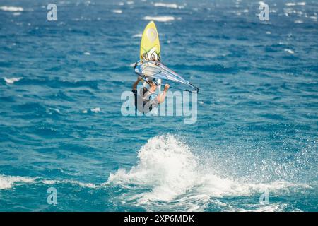 Algajola, Corse, France - 31 mai 2024 : un windsurfeur prend les airs au-dessus de fortes vagues au large d'Aregno plage à Algajola sur la côte méditerranéenne Banque D'Images
