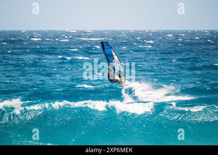Algajola, Corse, France - 31 mai 2024 : un windsurfeur prend les airs au-dessus de fortes vagues au large d'Aregno plage à Algajola sur la côte méditerranéenne Banque D'Images