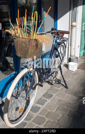 Vélo français avec panier de fleurs décoratif à l'extérieur d'un café français à Saint Valery sur somme, dans le nord de la France. Été 2024. Pittoresque. Excentrique. Banque D'Images