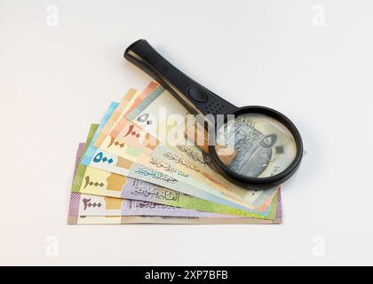 Billets de banque syriens avec loupe isolés sur fond blanc Banque D'Images