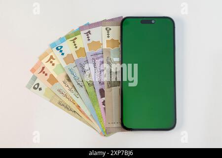 Billets de monnaie syriens et smartphone avec écran blanc vert isolé sur fond blanc Banque D'Images