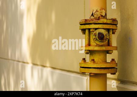 Tuyau de gaz au sol jaune sur le bâtiment. Soupape de commande de gros grunge. Système d'alimentation en gaz. Concept industriel. Banque D'Images