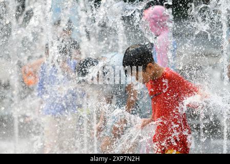 Séoul, Corée du Sud. 4 août 2024. Des enfants sud-coréens jouent dans l'eau par un après-midi chaud à la fontaine de la place Gwanghwamun. Avec l’alerte de vague de chaleur en vigueur en Corée du Sud, la température à Yeoju, à 64 kilomètres au sud-est de Séoul, a atteint 40 degrés Celsius le 4 août, la température la plus élevée depuis 2018. L'Administration météorologique sud-coréenne a prédit que la vague de chaleur se poursuivra pendant une semaine jusqu'au 14 août, car les températures diurnes resteront au-dessus de la normale, y compris 30 degrés Celsius et 36 degrés Celsius dans tout le pays. Banque D'Images