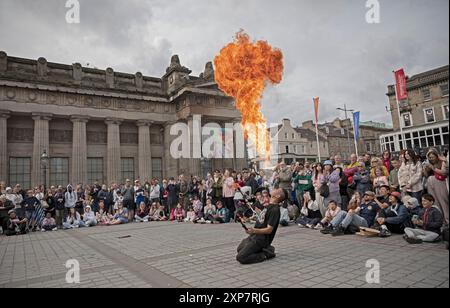 Édimbourg Écosse, Royaume-Uni. 4 août 2024. Temps nuageux avec rafales de vent et température de 19 degrés pour ceux qui sortent et se déplacent dans le centre-ville pour voir des artistes de rue. Photo : Chinnen du Japon souffle une boule de feu sur le terrain de Mound avec l'architecture de la National Gallery of Scotland derrière. Credit : Arch White/Alamy Live news. Banque D'Images