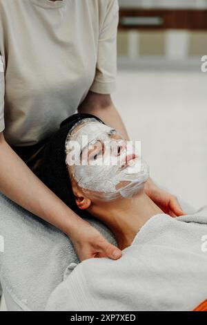 Soin spa relaxant pour une jeune femme avec masque facial pendant la séance de l'après-midi Banque D'Images