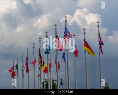 Des drapeaux colorés du monde entier flottent majestueusement dans la brise contre un ciel nuageux à l'extérieur de l'emblématique centre olympique dans le centre-ville de Lake Placid Banque D'Images