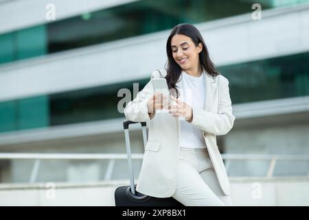 Femme en costume blanc en utilisant smartphone à l'aéroport Banque D'Images