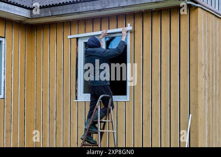 Finition extérieure de la façade de la maison à ossature, le constructeur installe des montants métalliques sur les fenêtres. Banque D'Images