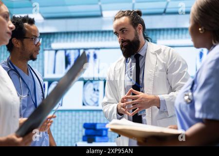 Radiologues équipe diversifiée examinant les radiographies pour discuter des soins prodigués aux patients dans un établissement de santé. Équipe de spécialistes de la santé qualifiés travaillant ensemble pour fournir un diagnostic et des plans de traitement précis. Banque D'Images
