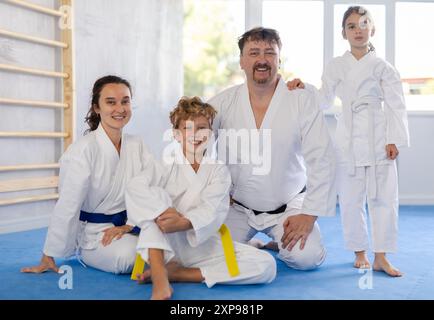 Couple marié et leurs enfants en kimono assis à genoux sur tatami dans la salle de gym Banque D'Images