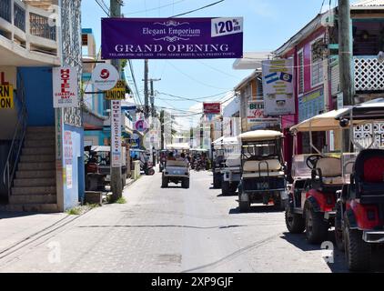 Middle Street, alias Pescador Drive, dans la ville de San Pedro sur Ambergris Caye, Belize. Les entreprises et les voiturettes de golf garées bordent la rue. Banque D'Images