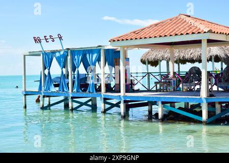 Une jetée ombragée avec des sièges et des rideaux bleus lors d'une journée ensoleillée à secret Beach, San Pedro, Belize. Banque D'Images
