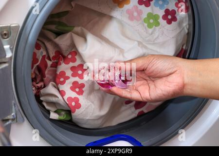 Gel pour dosette à linge à maintien manuel pour femme. Détergent à lessive. Linge sale dans la machine à laver. Banque D'Images