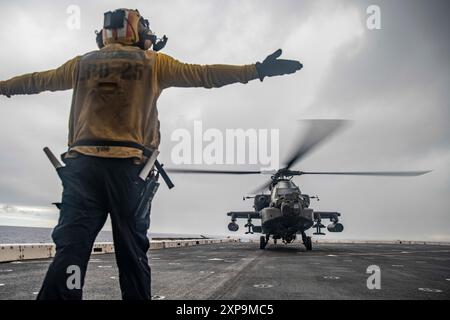 Un marin américain affecté au quai de transport amphibie USS Somerset (LPD 25) guide un AH-64 Apache de l'armée américaine attaché au 3e bataillon, 25e régiment d'aviation, 25e brigade d'aviation de combat, 25e division d'infanterie, alors qu'il se prépare au décollage de Somerset pendant les qualifications d'atterrissage de pont commun au large de la côte d'Hawaï 2 août 2024. Des éléments de la 15e Marine Expeditionary Unit sont actuellement embarqués à bord du Boxer Amphibious Ready Group qui mène des opérations de routine dans la 3e flotte américaine. (Photo du corps des Marines des États-Unis par le sergent Patrick Katz) Banque D'Images