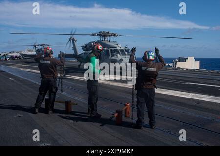 240722-N-IJ966-1154 OCÉAN PACIFIQUE (22 juillet 2024) des marins montrent des cales et des chaînes dégagées aux pilotes d'un hélicoptère MH-60S Sea Hawk, affecté au Helicopter Sea combat Squadron (HSC) 14, sur le pont d'envol du porte-avions USS Abraham Lincoln de classe Nimitz (CVN 72). Abraham Lincoln, navire amiral du Carrier Strike Group Three, mène des opérations de routine dans la zone d'opérations de la 3e flotte américaine. En tant que partie intégrante de la flotte américaine du Pacifique, la 3rd Fleet exploite des forces navales dans l'Indo-Pacifique en plus de fournir une formation réaliste et pertinente nécessaire pour exécuter parfaitement Banque D'Images