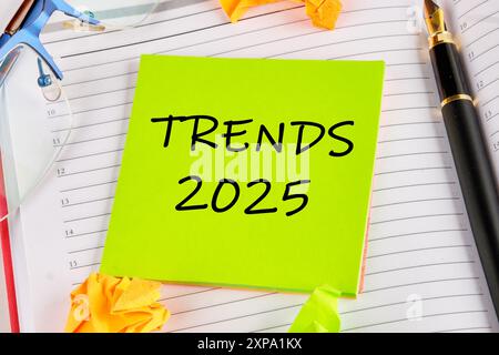 Symbole tendances conceptuelles 2025. Copier l'espace. Tendances 2025 mots écrits sur un autocollant vert clair posé sur le carnet Banque D'Images