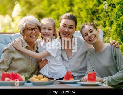 Famille heureuse passant du temps ensemble le matin d'été. Famille assise dans le jardin et profitant de la conversation. Banque D'Images